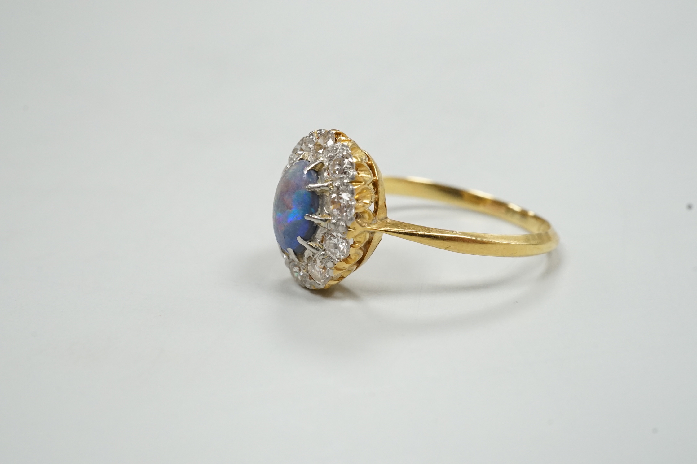 An early 20th century 18ct, black opal and diamond set oval cluster ring, size O, gross weight 2.8 grams.